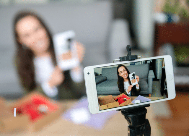 woman recording herself in a video via a phone on a tripod