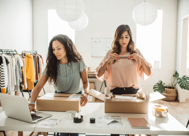 two women packing up boxes for a clothing shop