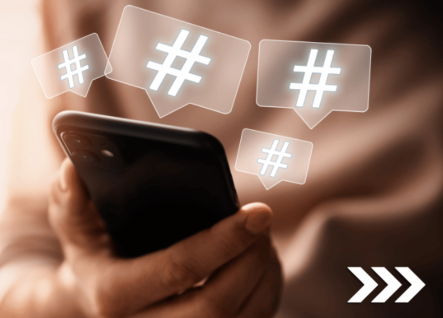 hands holding phone with hashtags floating up relating to how to use hashtags on social media