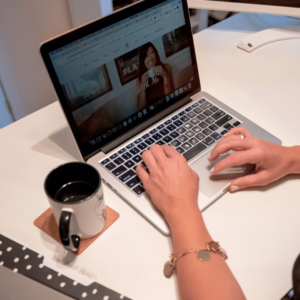 woman's hands on laptop keyboard with a cup of coffee nearby