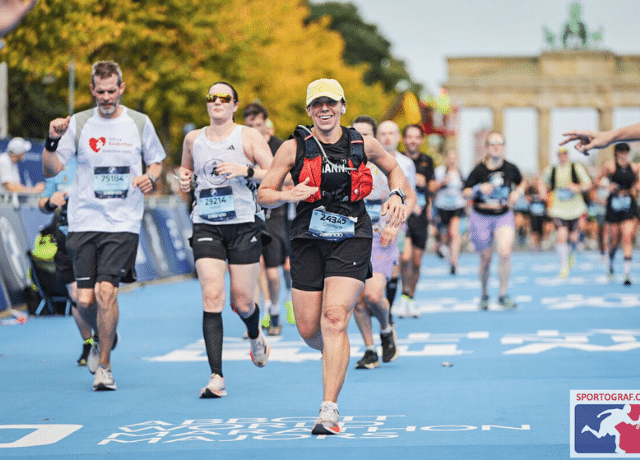 woman crosses marathon finish line in Berlin relating to business lessons from marathon method