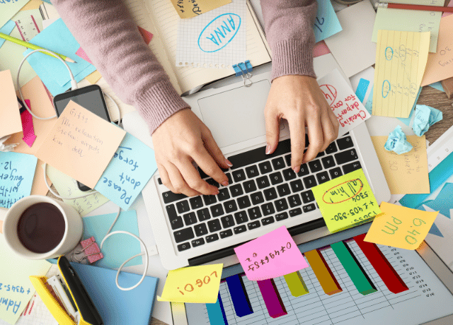 hands over keyboard on crowded desk relating to when it's time to hire a marketing agency