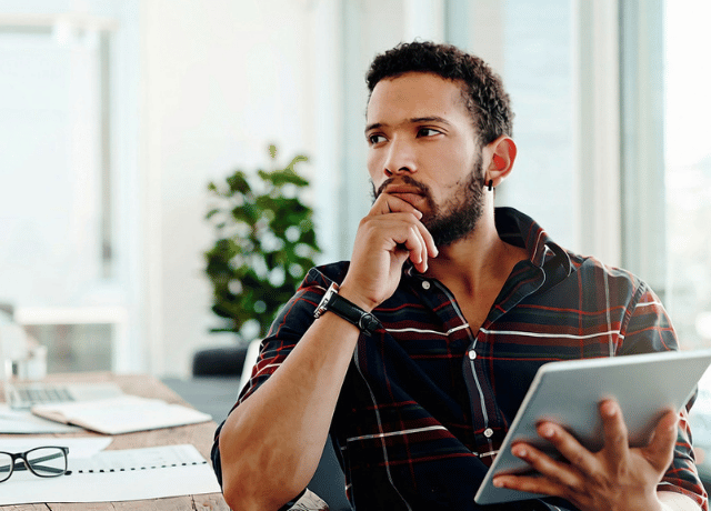 man looking pensive at tablet relating to marketing consultant vs. marketing agency